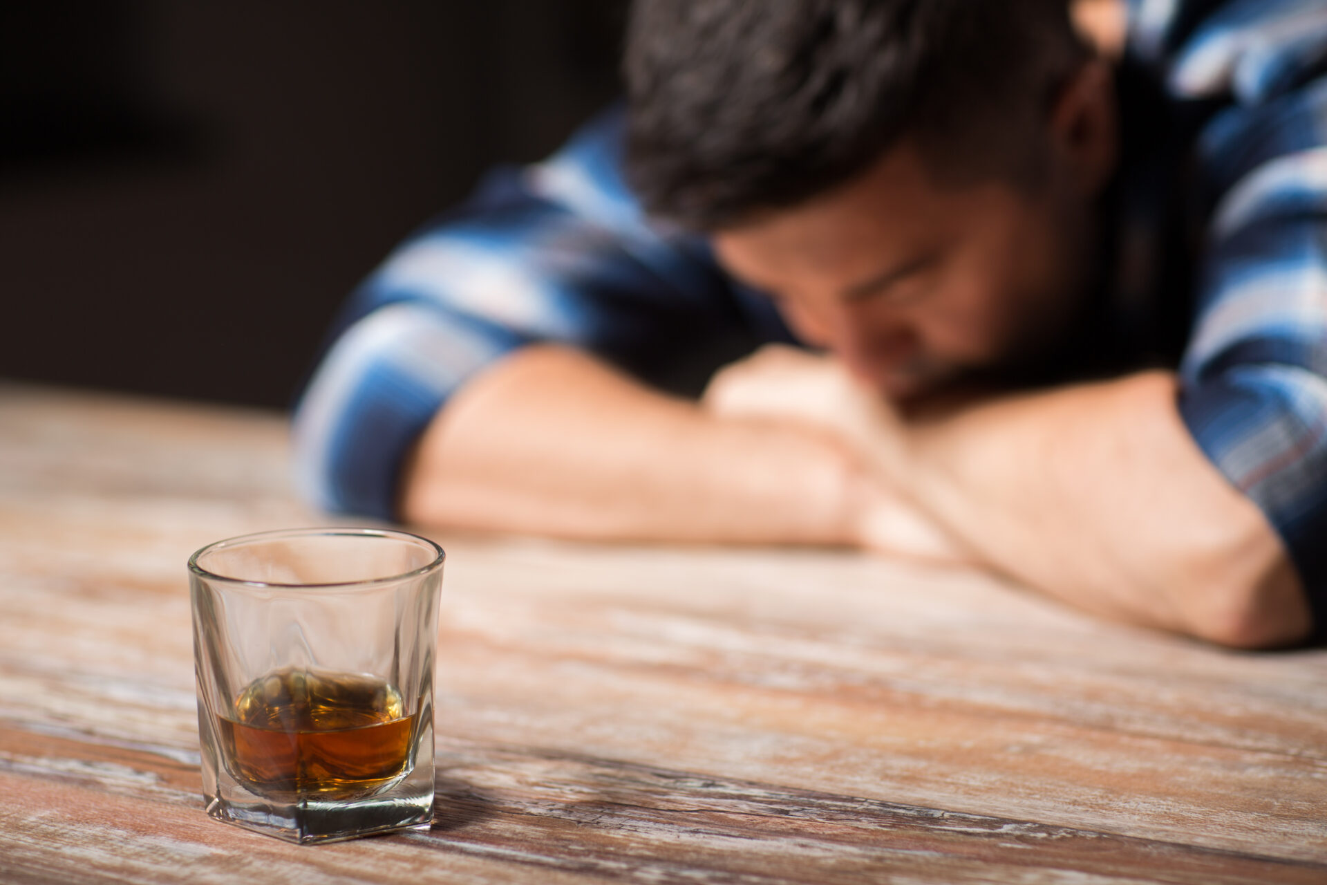 drunk man with glass of alcohol on table at night
